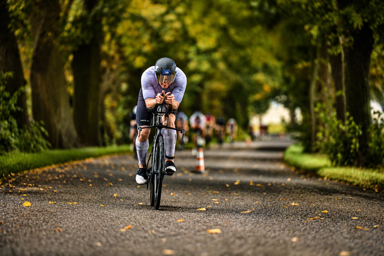 Kolarz w alei drzew podczas zawodów triathlonowych